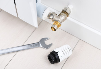A wrench lies on the floor near the thermostat of a heating battery in an apartment, office. Heating recovery.