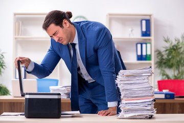 Young male employee making copies at copying machine