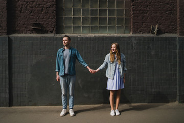 Romantic and happy caucasian couple in casual clothes walking together through the city streets. Love, relationships, romance, happiness concept. Man and woman holding hands and smiling.