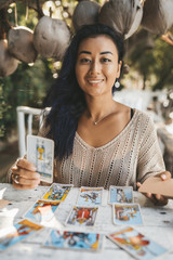 Woman is reading Tarot cards sitting at the table outdoors