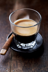 Coffee in glass cup on rustic wooden background. Close up.