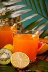 Glasses of tropical exotic multifruit juice on a palm leaves.