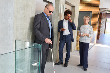 Blinder Mann mit Blindenstock und Business Kollegen