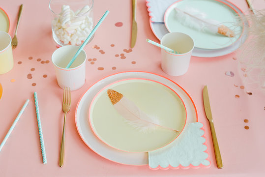 Decorative table setting in pastel colors with pink tablecloth, paper colorful dishes, cups, golden cutlery. birthday for girl, baby shower or hen party decoration.