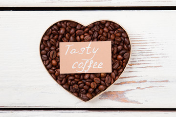 Tasty coffee love. Brown coffee beans arranged in a heart shape. Flat lay top view.