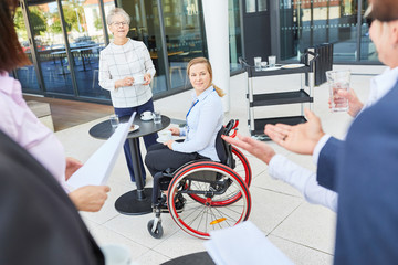 Geschäftsfrau im Rollstuhl im Gespräch mit Kollegen
