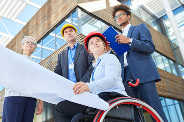 Frau als Architekt im Rollstuhl mit Bauplan