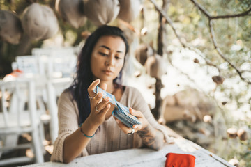 Woman is reading Tarot cards sitting at the table outdoors
