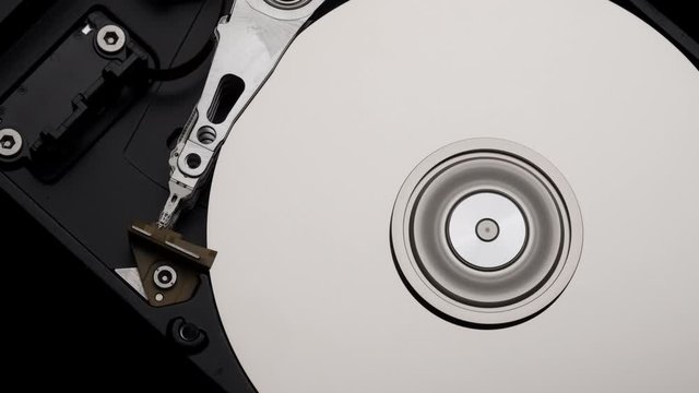 Macro, Close-Up of Computer Hard Disk Drive Spinning and Writing then Rotation Slow Down. 4k