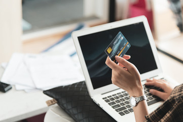 Young Asian woman using credit card for shopping online at her home