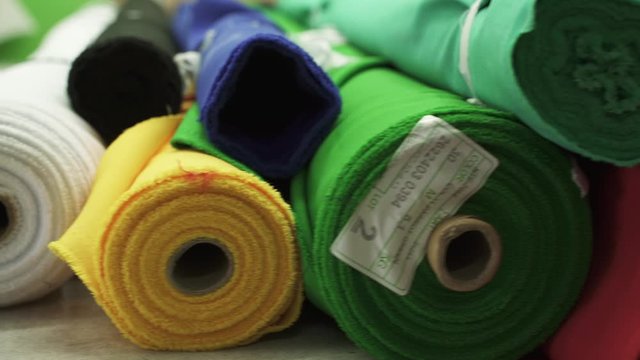 Rolls of fabric of different colors in stock