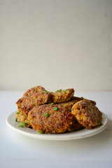 Cutlets with green onion on top on a white background.