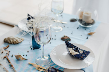 Party table setting in sea style. Elegant plates, glasses, in blu? colors. Paper boats with marshmallow. Birthday or baby shower boy concept.