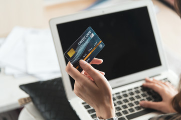 Young Asian woman using credit card for shopping online at her home