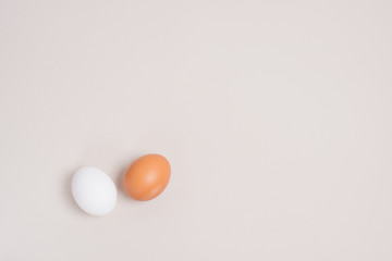 two eggs white and brown on a beige background