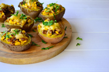 Stuffed baked potato with mushrooms, onion and corn on a white background.