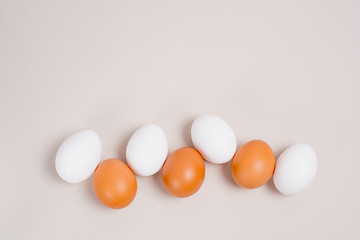 brown and white eggs laid out in a single line from the bottom of the background, top view