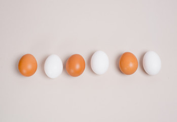 brown and white eggs laid out in a line in the middle of the background, top view