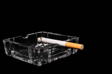 glass ashtray and burning cigar with black background