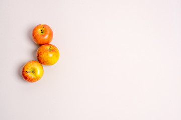 three apples on a beige background from the left side top view