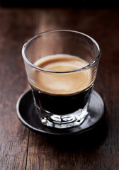 Coffee in glass cup on rustic wooden background. Close up.
