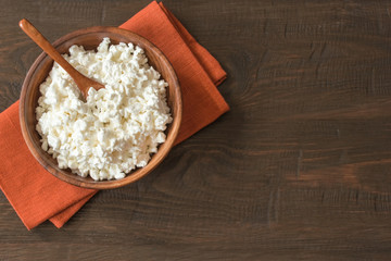 cottage cheese in a wooden bowl and spoon on the table top view. background with cottage cheese in a bowl standing on a napkin. copy of the space. the curd was flat in the bowl.