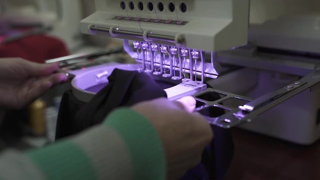 woman inserts a hoop into the machine for embroidery logo