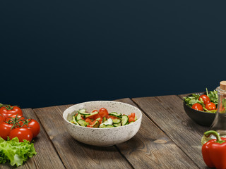 Fresh vegetable salad in white bowl on wooden table on blue background with copyspace. Healthy vegetarian lifestyle.