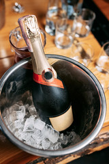 a bottle of champagne in a bucket with ice on the background of a wooden table