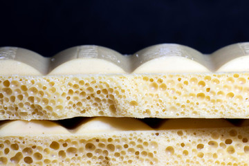 Broken bar of white chocolate on a black background. A delicious bar of milk chocolate. Selective focus