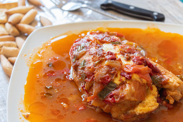 Chicken breast stuffed with ham and cheese with vegetables in porridge on white plate