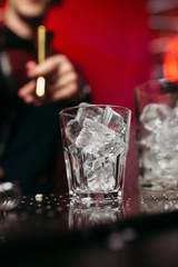 glass filled with ice on the background of the bartender