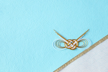 金と白の水引飾りと水色の和紙と青海波の和紙の背景