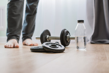 dumbbells for sports at home on the wooden floor for the period of isolation. disk for bodybuilding. man on a blurry background