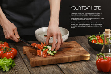 Woman cooking fresh healthy vegetable salad on board on wooden table. Female hands with sample text.