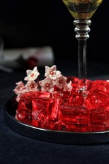 Sweet jelly dessert, design food, creative meals with vanilla flowers in dark mood on black background