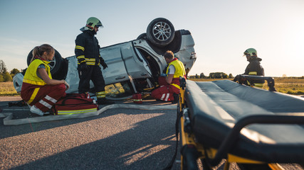 On the Car Crash Traffic Accident Scene: Paramedics and Firefighters Rescue Injured Victim Trapped...