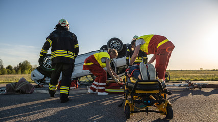 On the Car Crash Traffic Accident Scene: Paramedics Saving Life of a Female Victim who is Lying on...