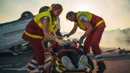 On the Car Crash Traffic Accident Scene: Paramedics Saving Life of a Female Victim who is Lying on...