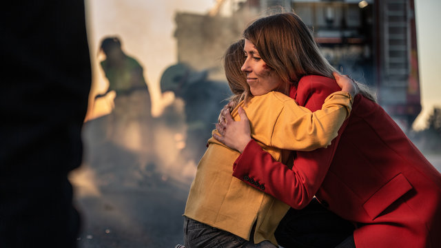 Car Crash Traffic Accident: Injured Young Girl Reunites with Her Loving Mother. In the Background Fire engine and Courageous Paramedics and Firemen Save Lives