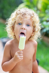 Happy curly boy eating ice cream