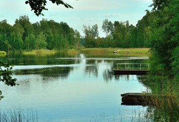 Part of the Bank with trees and a wooden platform of the Vuoksa river on a summer day