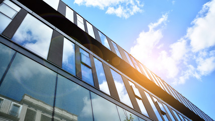 Obraz premium Modern building in the city with sunlight. Glass wall of an office building in the sunlight. Office building window close up with sunrise, reflection and perspective.