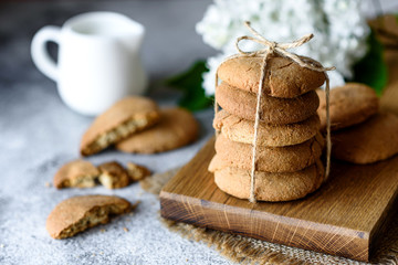 Homemade oatmeal cookies on a wooden cutting board on old table background