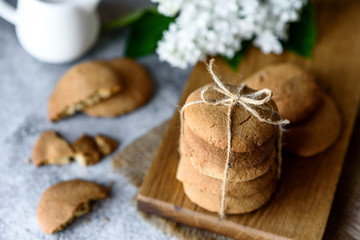 Homemade oatmeal cookies on a wooden cutting board on old table background