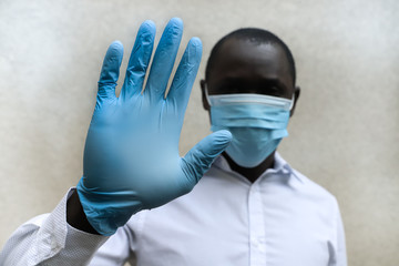 African medical staff with face mask and raised hands with rubber gloves