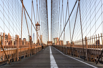 Auf der Brooklyn Bridge zwischen Manhattan und Brooklyn mir dem Blick nach Manhattan zur frühen Morgenstunde im Sommer-nur ein einziger Tourist in der Ferne