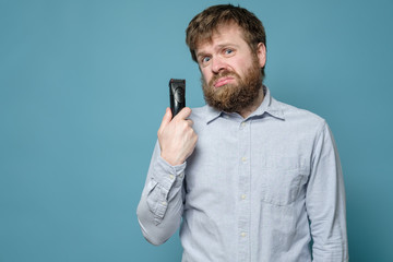 Funny shaggy man with a trimmer has not been in the barbershop for a long time and will have to cut...