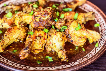 fried chicken with sweet herbs on a plate close-up. background with cooked chicken and green onions in a ceramic bowl close-up.