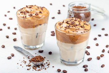Trendy korean drink Dalgona coffee with ice, garnished with grated chocolate, light gray background, horizontal